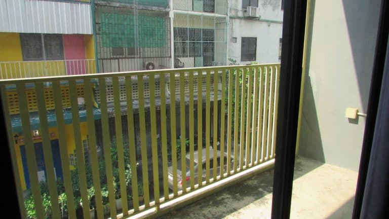 Home Stay 12 a balcony with yellow railings and buildings in the background